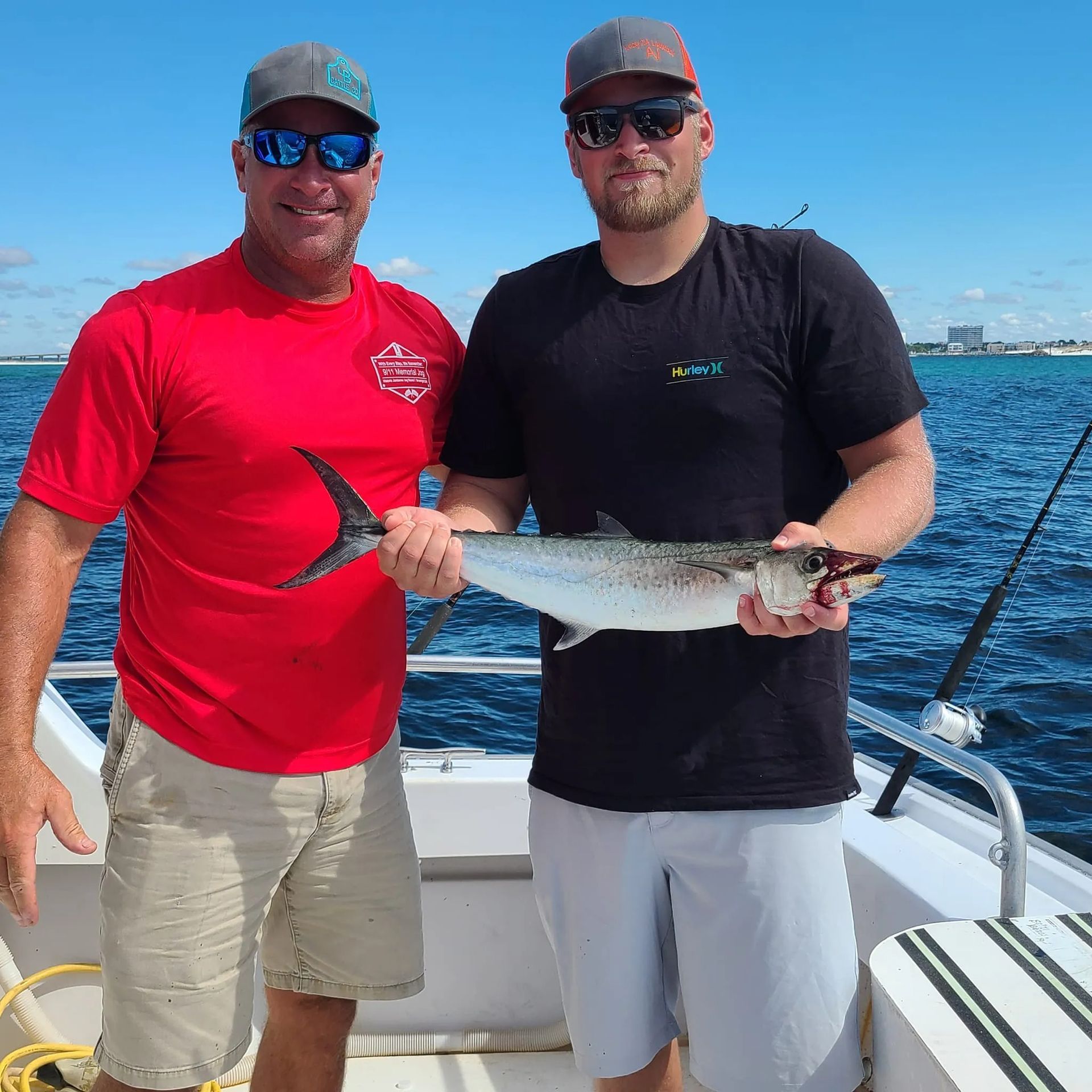 Two men are standing on a boat holding a fish.