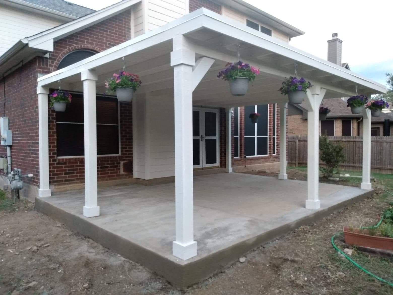 A covered patio with flowers hanging from the pillars