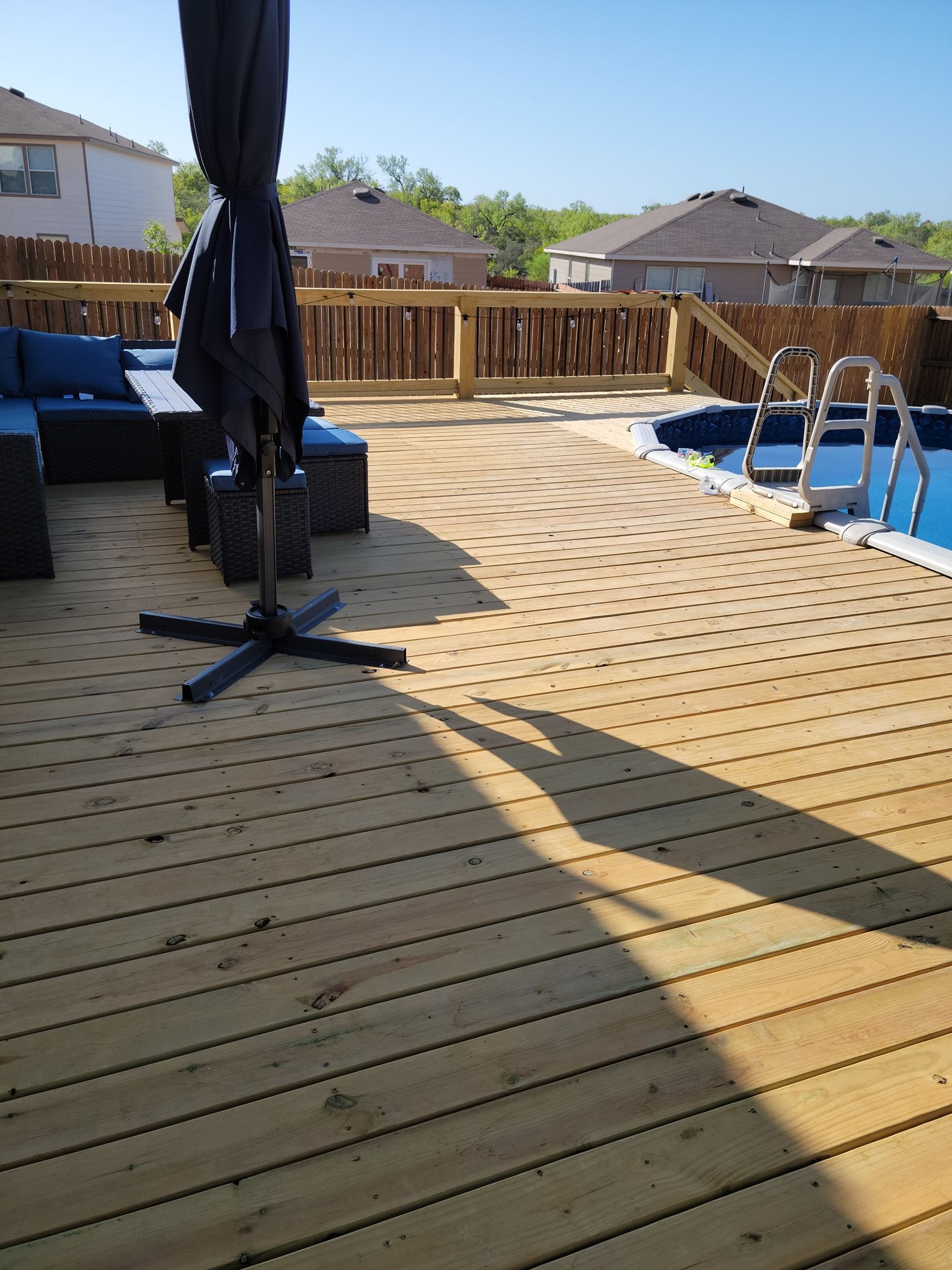 A wooden deck with a swimming pool in the background