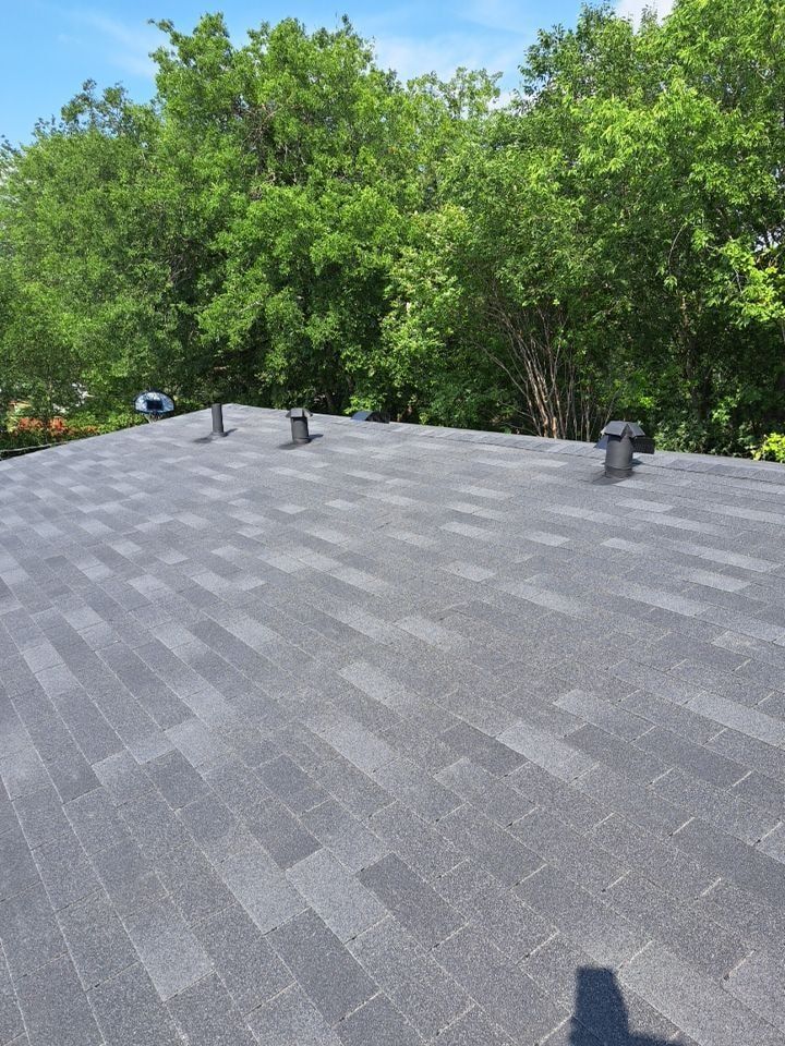 A roof with a lot of shingles and trees in the background