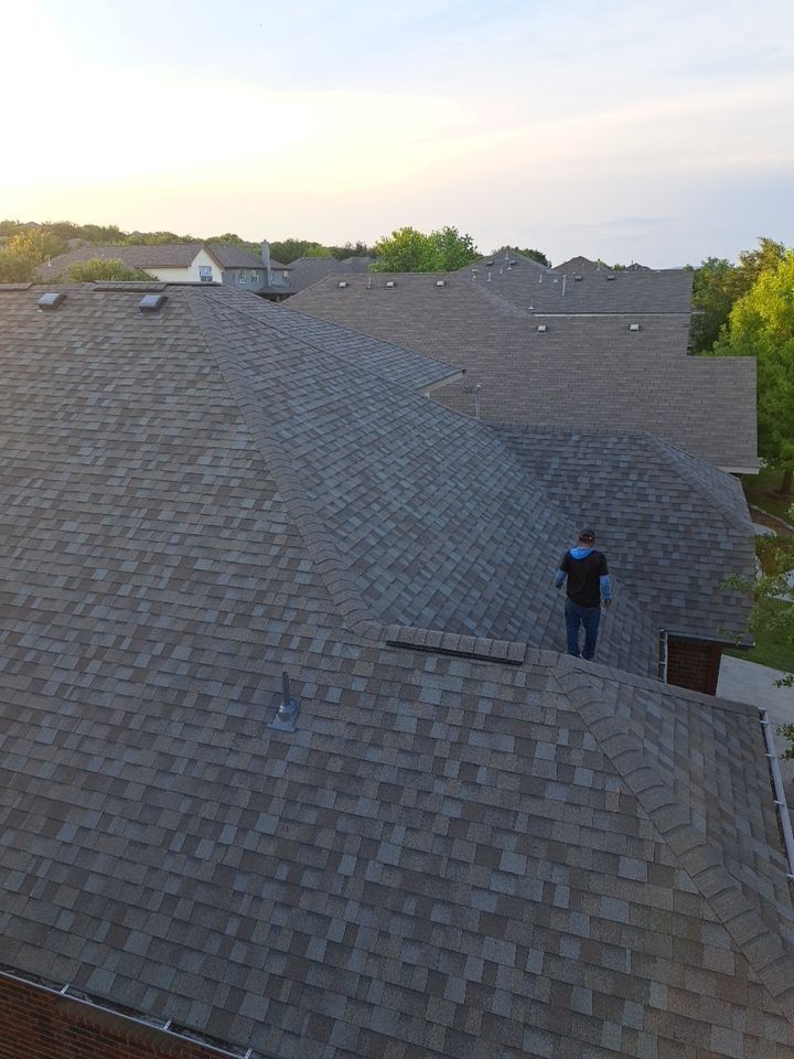 A man is standing on top of a large roof.