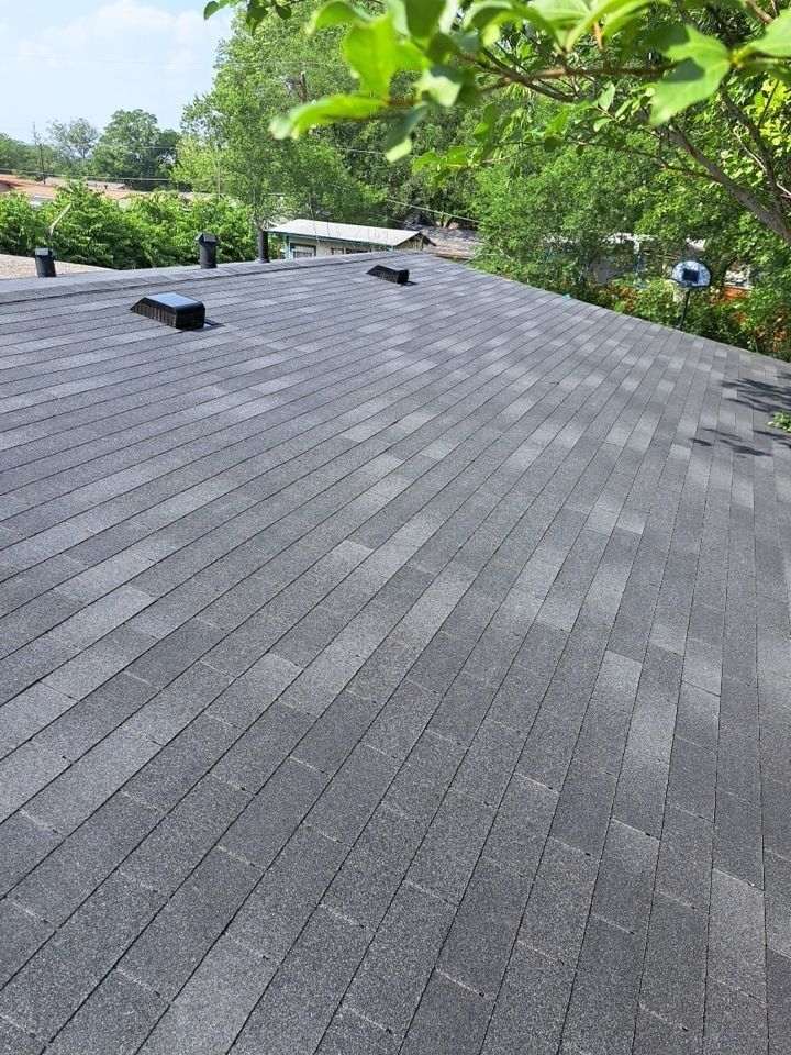 A roof with a lot of shingles on it and trees in the background.