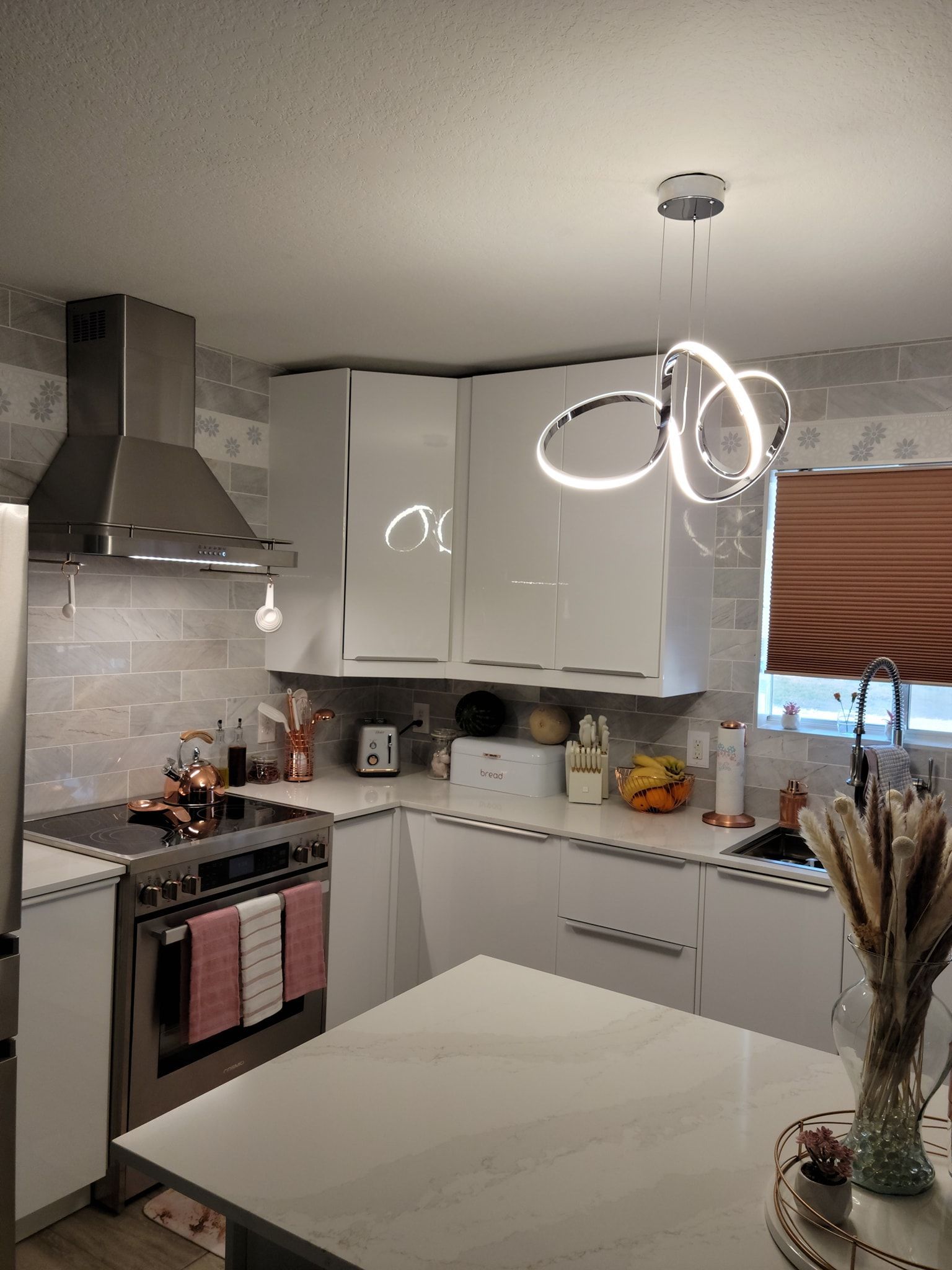 A kitchen with white cabinets , a stove , a refrigerator , and a table.