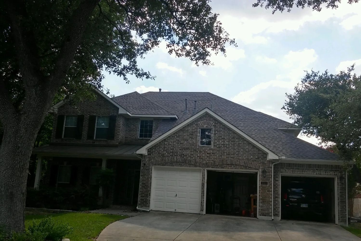 A large brick house with two garages and a tree in front of it.