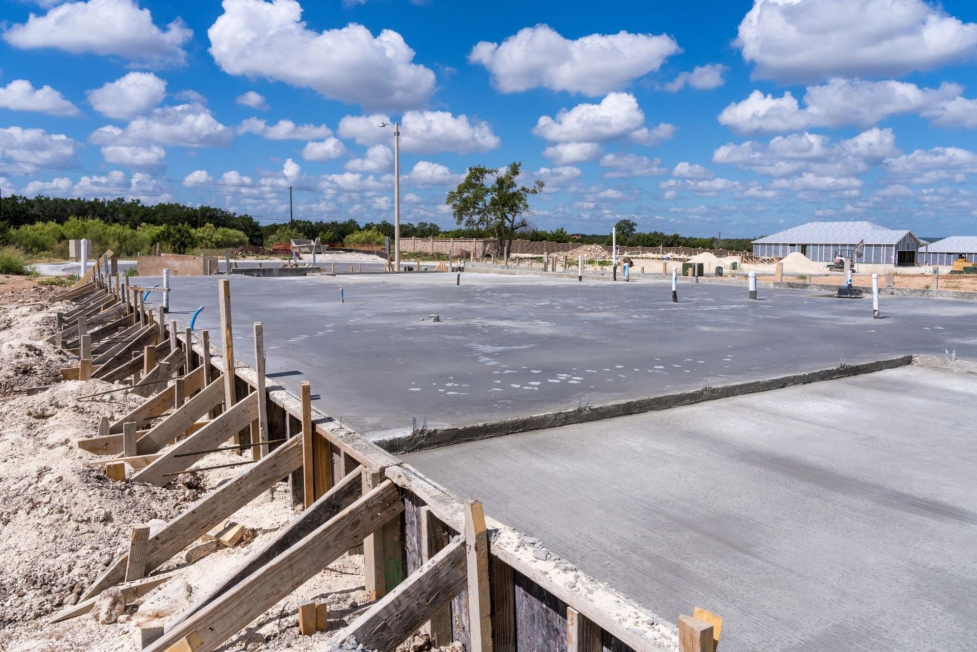 Woman in straw hat smiles, holding wine glass near a lake.