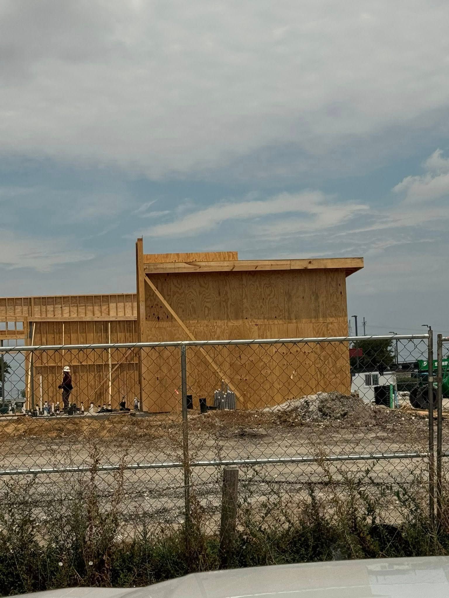 Woman in straw hat smiles, holding wine glass near a lake.