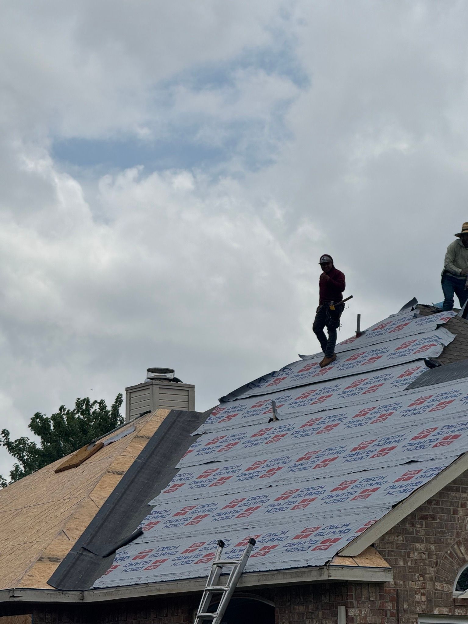 Woman in straw hat smiles, holding wine glass near a lake.