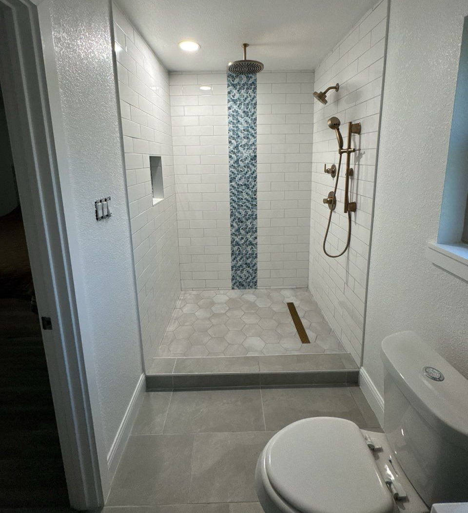 Woman in straw hat smiles, holding wine glass near a lake.