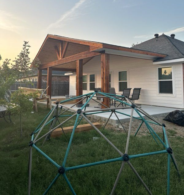 Woman in straw hat smiles, holding wine glass near a lake.
