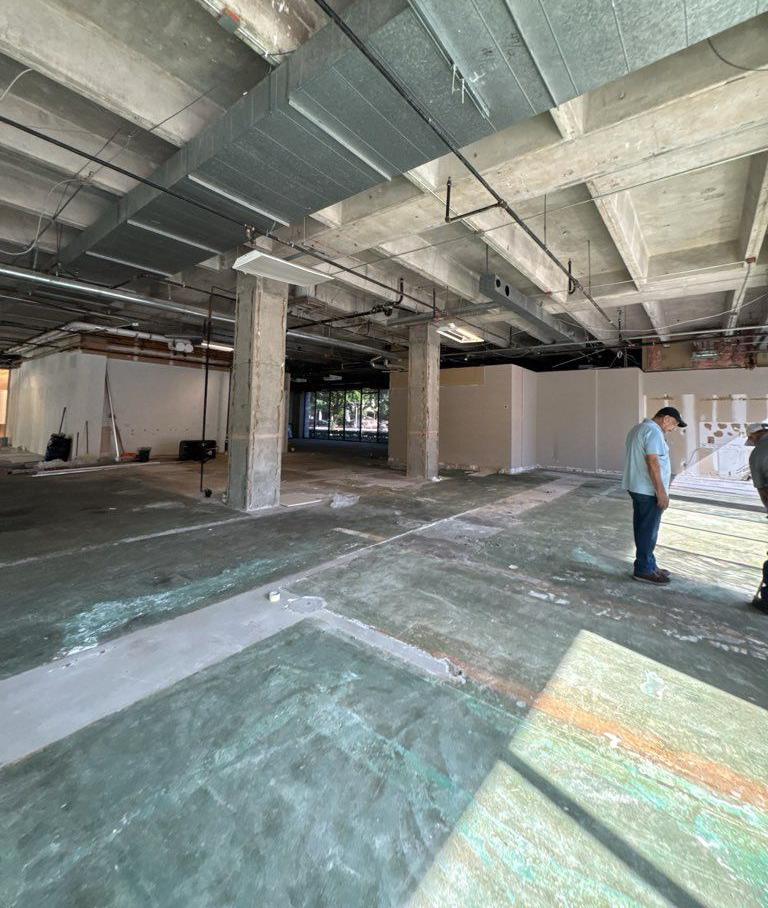 Woman in straw hat smiles, holding wine glass near a lake.
