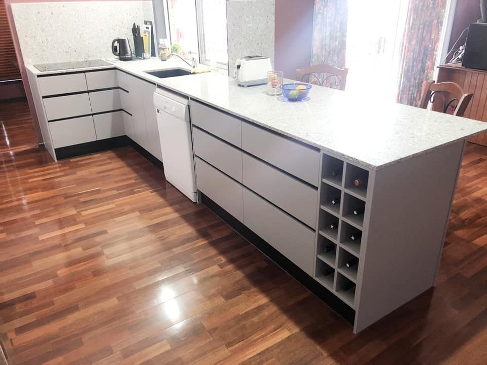 Modern White Kitchen With a Large Island, Wine Rack, and Wooden Floors — Nyblad Construction in Maroochydore, QLD