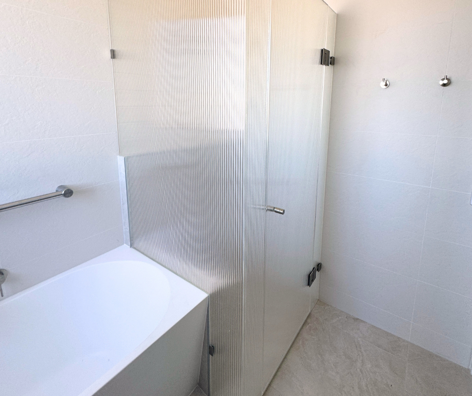 White Bathroom With a Glass Shower Enclosure, a Bathtub, and Wall Hooks — Nyblad Construction in Caloundra West, QLD