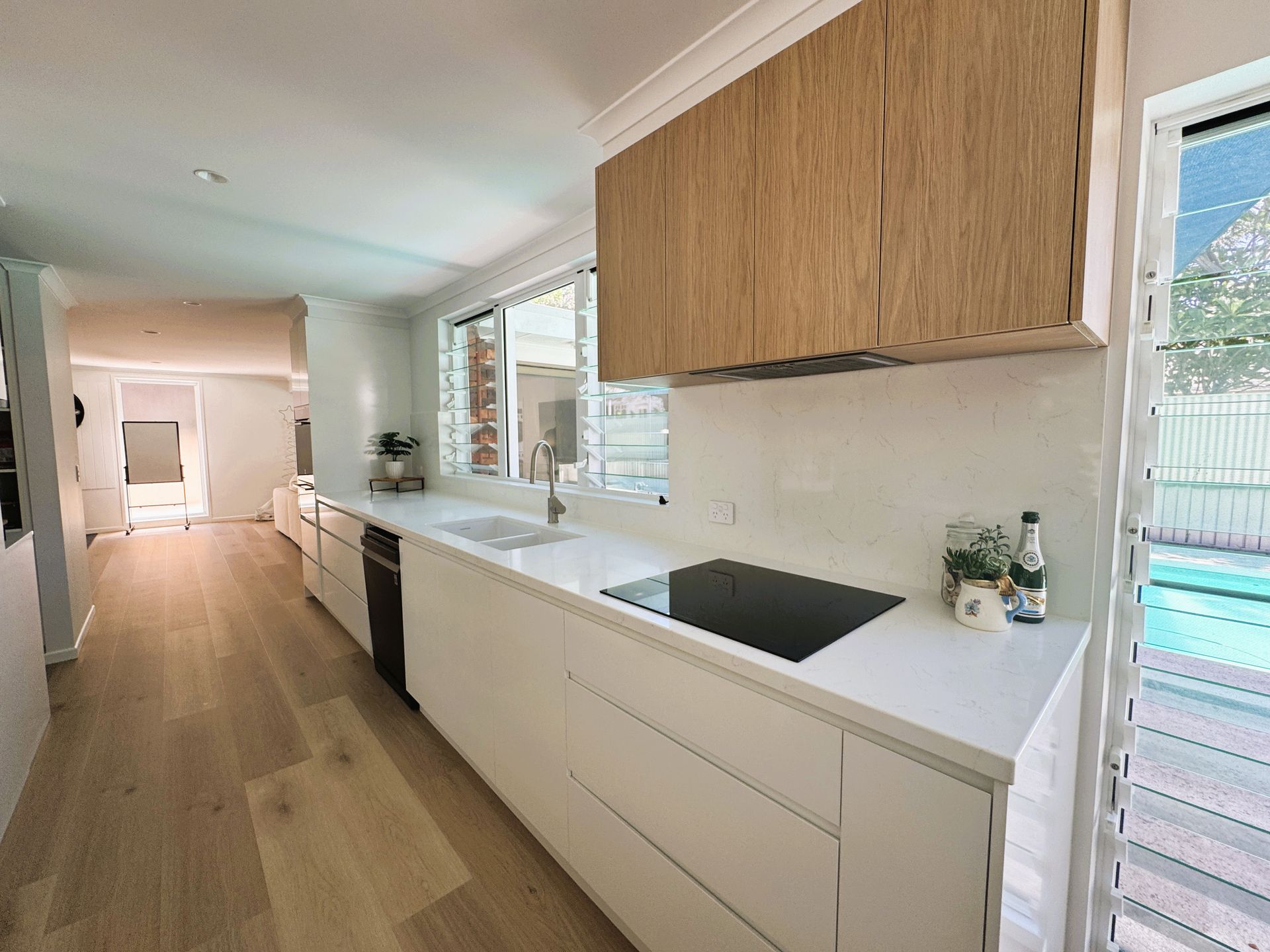 Family-friendly galley kitchen with white cabinetry and timber overhead cupboars