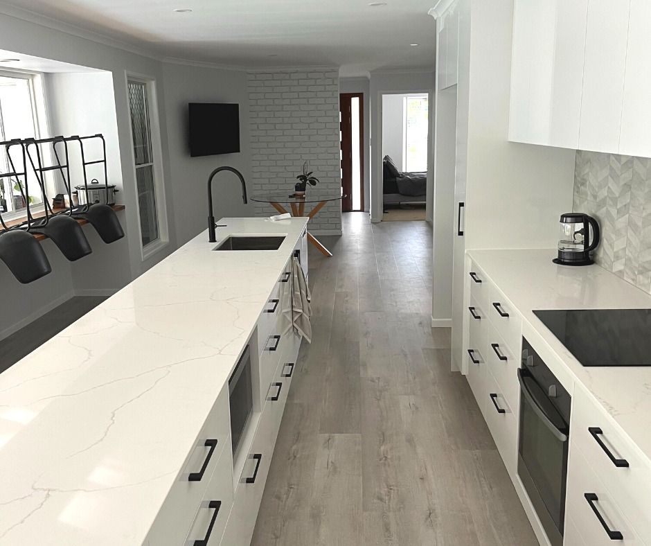 Modern Kitchen With Long White Countertop, Black Accents, and Light Wood Floors — Nyblad Construction in Caloundra, QLD