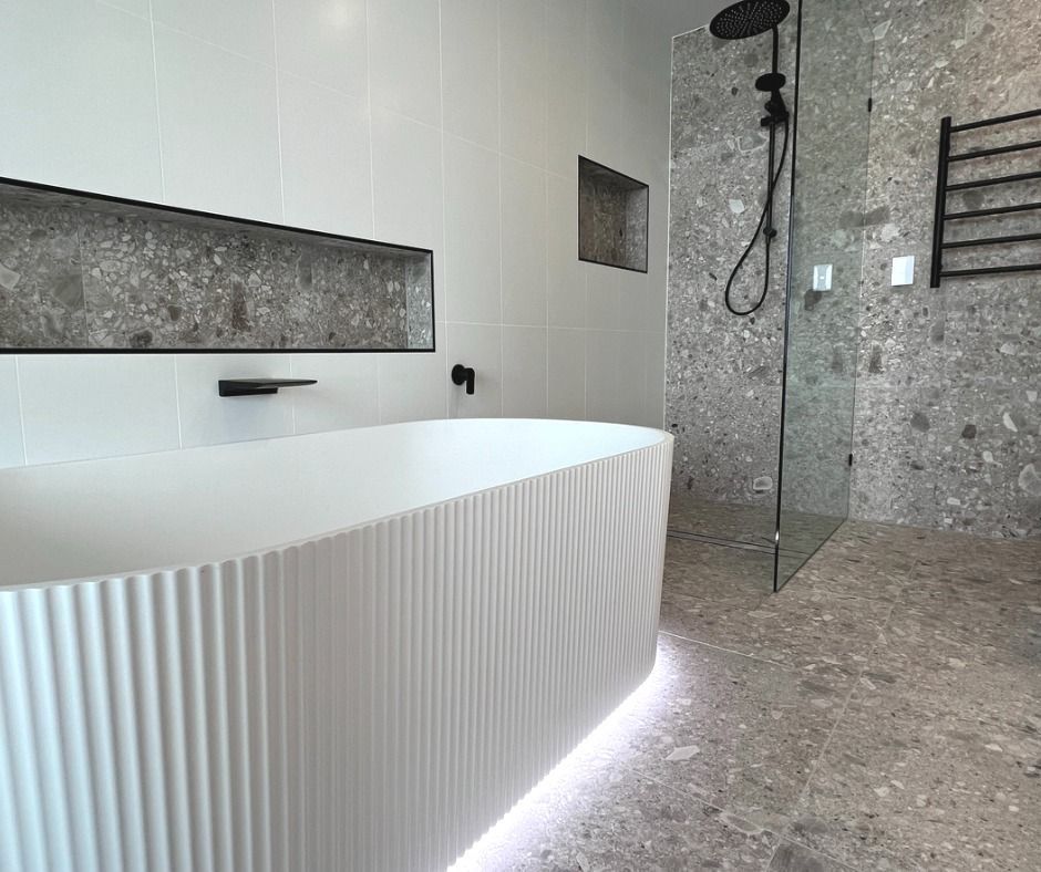 White Fluted Bathtub, Terrazzo Shower, Black Fixtures, Built-in Shelf, and a Heated Towel Rack — Nyblad Construction in Maroochydore, QLD