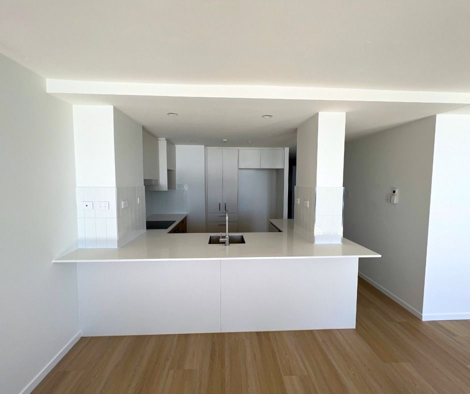 Open-plan Kitchen With White Cabinets, Countertops, and Bar — Nyblad Construction in Caloundra, QLD