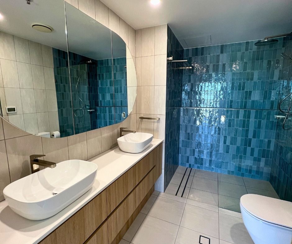 Modern Bathroom With Blue Tiled Shower, Wood Vanity, White Sinks, and Large Mirror — Nyblad Construction in Caloundra, QLD