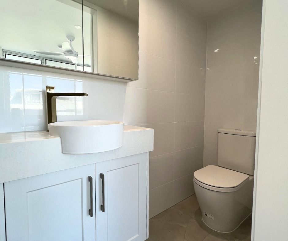 White Bathroom With a Sink, Cabinet, and Toilet — Nyblad Construction in Coolum, QLD