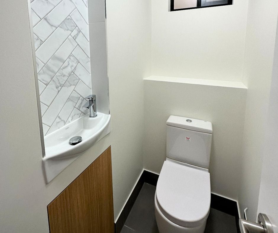 Small, Modern Bathroom With White Toilet, Marble Sink, and Wood Panel — Nyblad Construction in Buderim, QLD