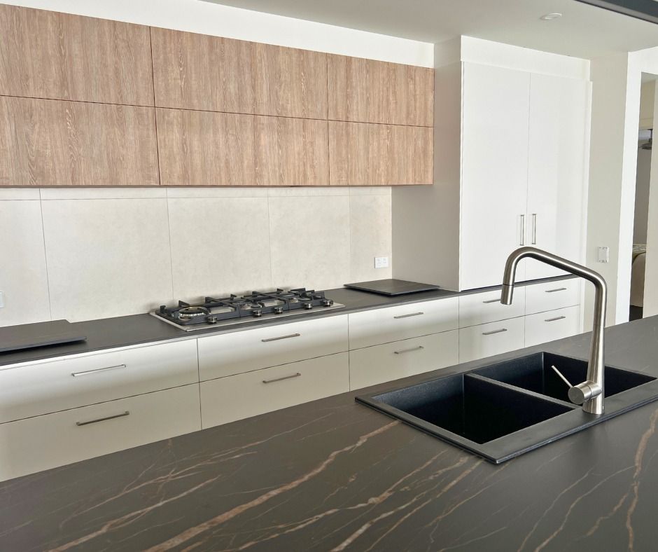 Modern Kitchen With Dark Countertops, White Cabinets, Wood Upper Cabinets, and a Stainless Steel Faucet — Nyblad Construction in Coolum, QLD