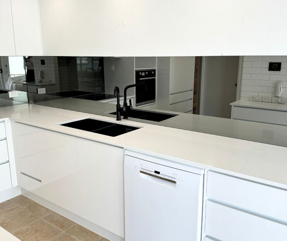 Kitchen With Reflective Mirrored Backsplash, Black Faucet, and White Appliances — Nyblad Construction in Coolum, QLD