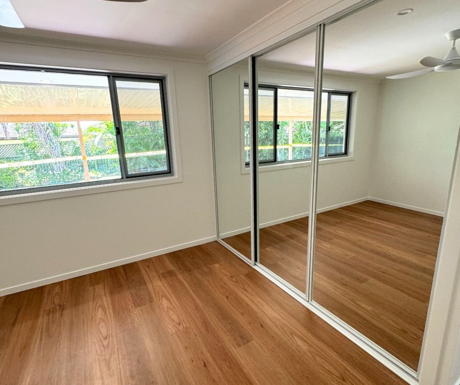 Empty Bedroom With Wood Flooring, Large Mirrored Closet, and Two Windows — Nyblad Construction in Coolum, QLD