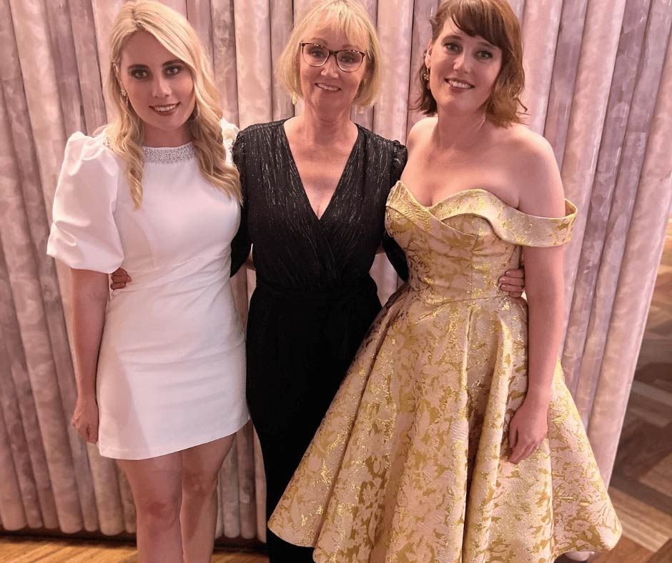 Three Women In Dresses Are Posing For A Picture Together — Nyblad Construction in Caloundra West, QLD