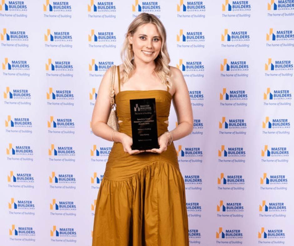 A Woman In A Yellow Dress Is Holding An Award — Nyblad Construction in Caloundra West, QLD