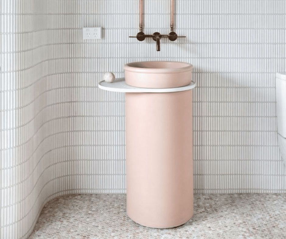 A Bathroom With A Pink Pedestal Sink And White Tiles — Nyblad Construction in Caloundra West, QLD