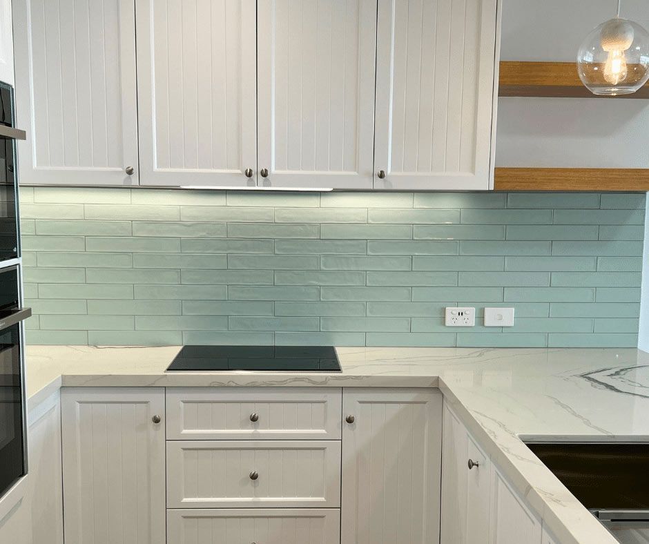 A Kitchen With White Cabinets Green Tile Wall And Outlet — Nyblad Construction in Caloundra West, QLD