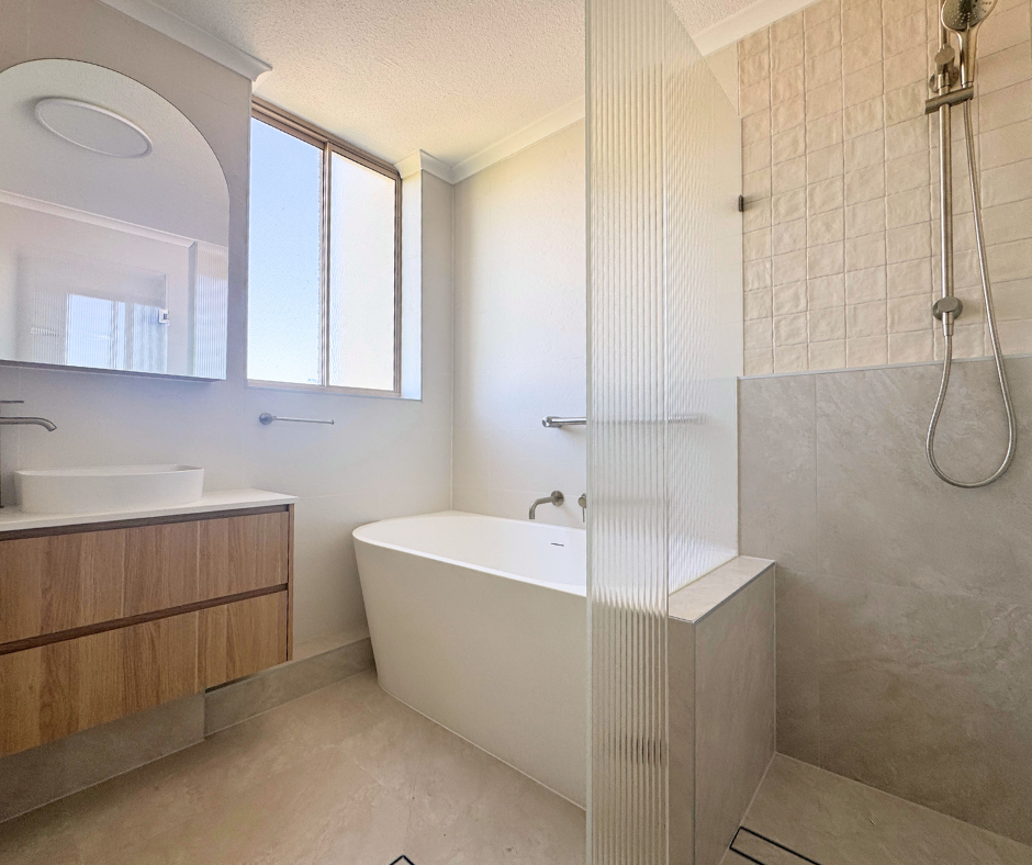 bathroom featuring warm-toned tiles , white bath and timber cabinetry with white stone benchtop 