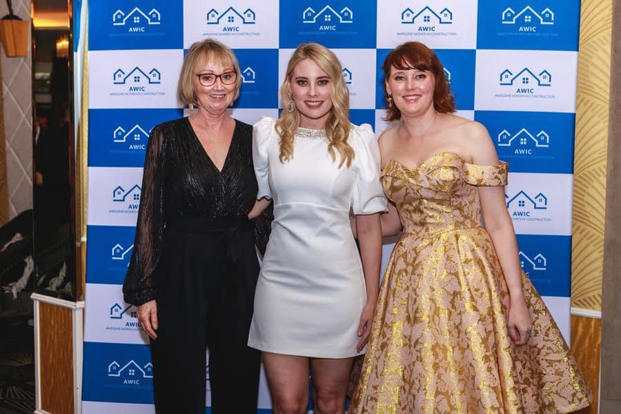 Three Women Are Posing For A Picture In Front Of A Blue And White Backdrop — Nyblad Construction in Caloundra West, QLD