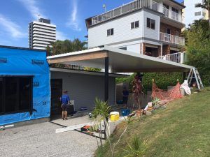 A Man Is Standing In Front Of A House Under Construction — Nyblad Construction in Caloundra West, QLD