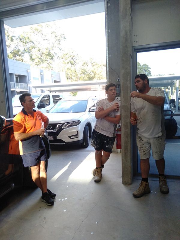 Three Men Are Standing Next To Each Other In A Garage — Nyblad Construction in Caloundra West, QLD