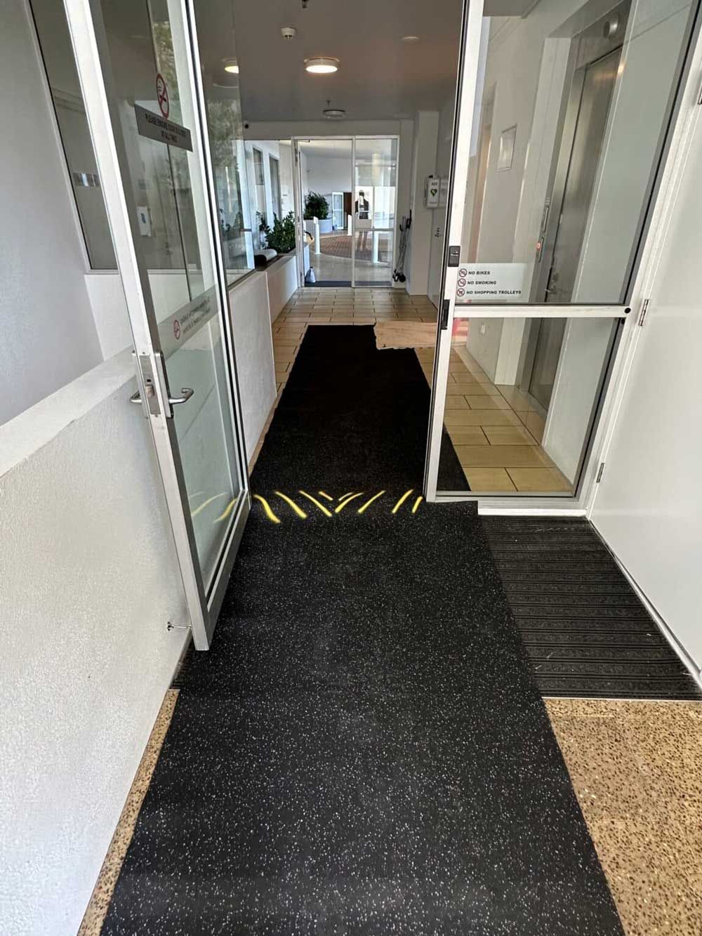 A Hallway With A Black Mat On The Floor And A Door — Nyblad Construction in Caloundra West, QLD