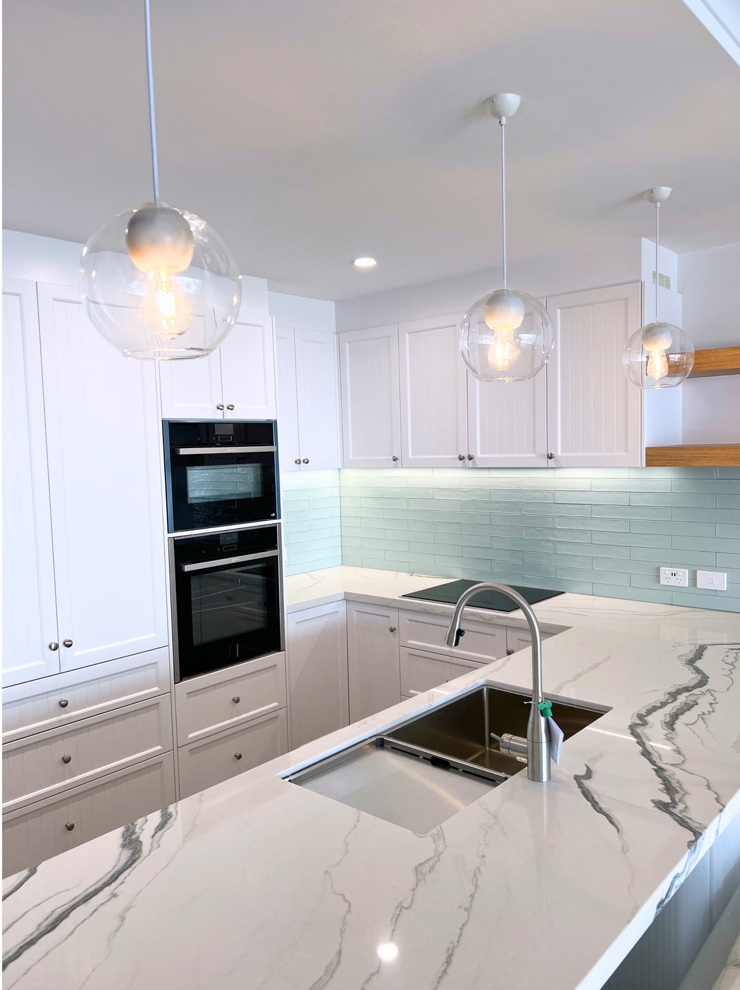 A Kitchen With White Cabinets And White Pendant Lights — Nyblad Construction in Caloundra West, QLD