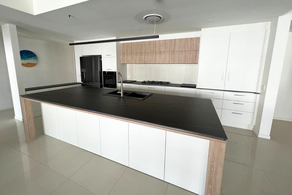 Kitchen With White Cabinets and a Black Counter Top — Nyblad Construction in Caloundra West, QLD