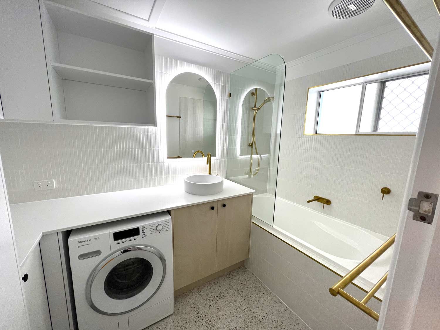 A Beautiful Bathroom With A Washing Machine, Sink, And Bathtub — Nyblad Construction in Caloundra West, QLD