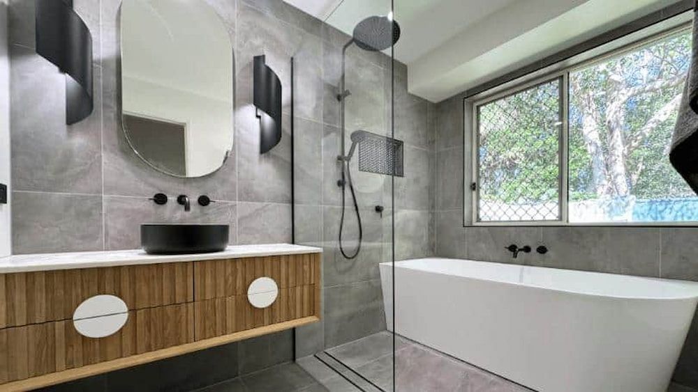 A Bathroom With a Tub, Sink, Mirror, and Shower — Nyblad Construction in Caloundra West, QLD