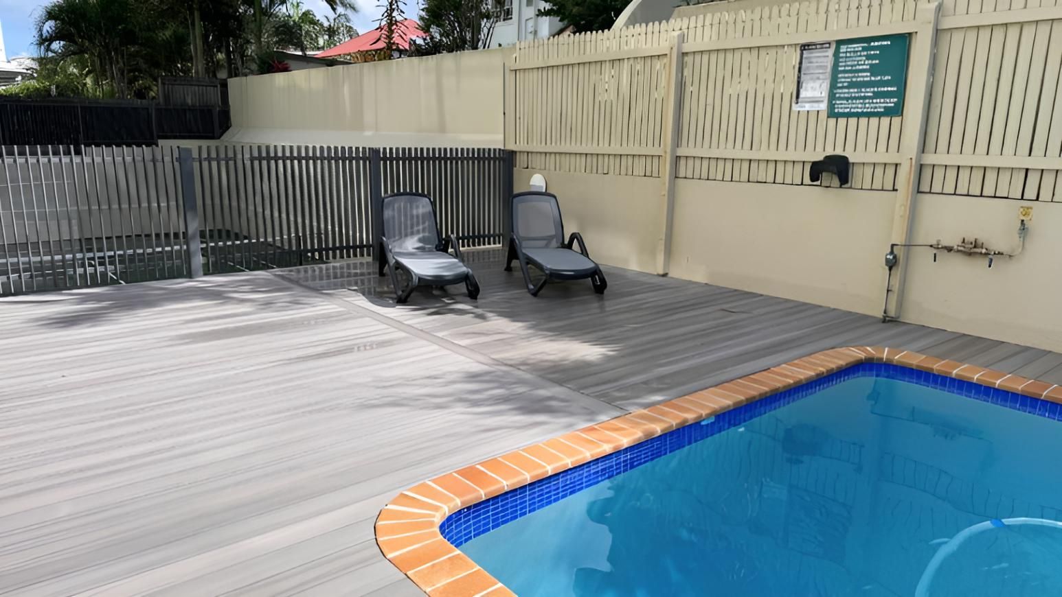 Swimming Pool With a Wooden Deck and Chairs — Nyblad Construction in Caloundra West, QLD