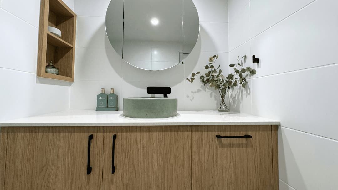 A Bathroom with A Sink , Mirror and Wooden Cabinets — Nyblad Construction in Caloundra West, QLD