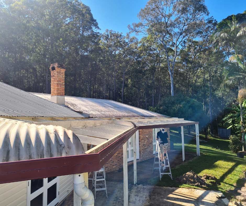 A Man Is Standing On A Ladder On The Porch Of A House — Nyblad Construction in Caloundra West, QLD