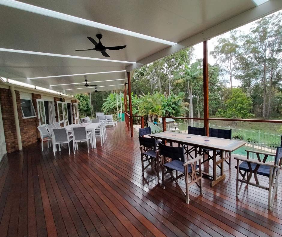 A Large Wooden Deck With Tables And Chairs And A Ceiling Fan — Nyblad Construction in Caloundra West, QLD