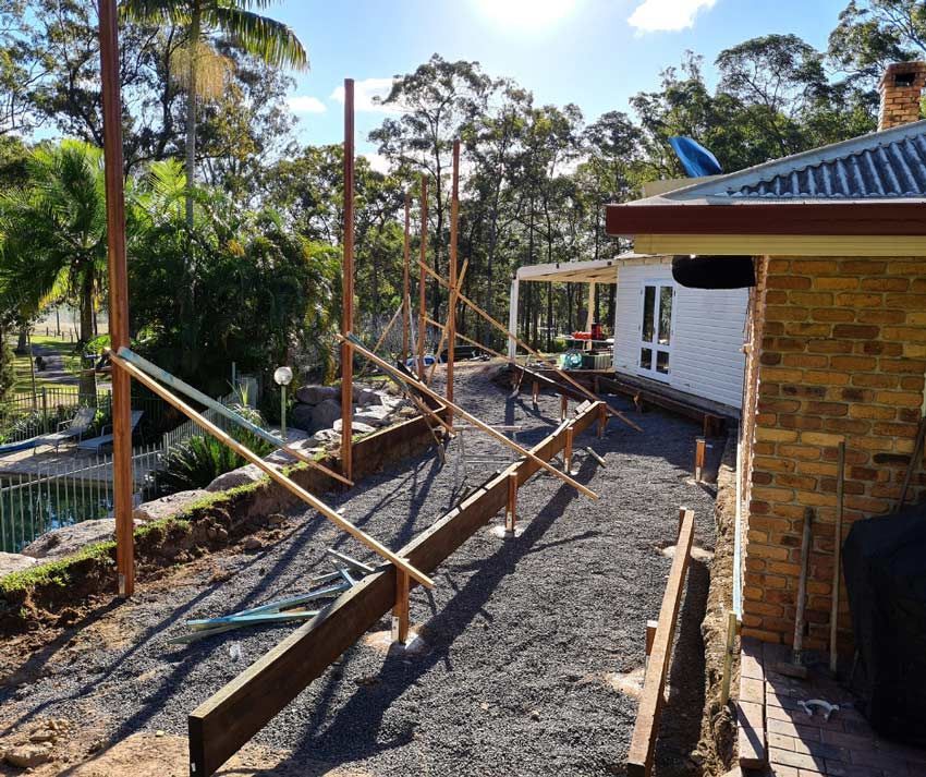 A Brick House Is Being Built With A Lot Of Wooden Beams — Nyblad Construction in Caloundra West, QLD