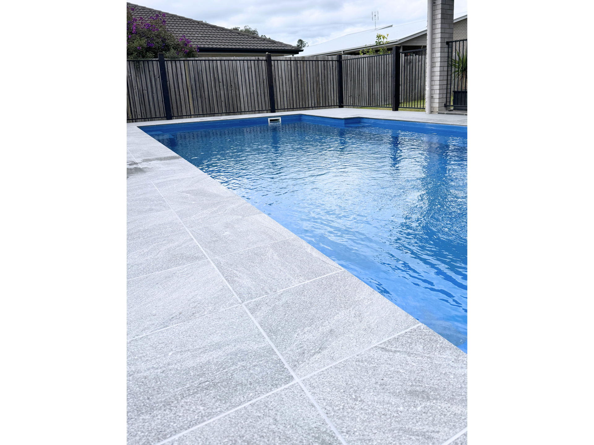 A Pool With Grey Tiles And A Black Fence — Nyblad Construction in Caloundra West, QLD