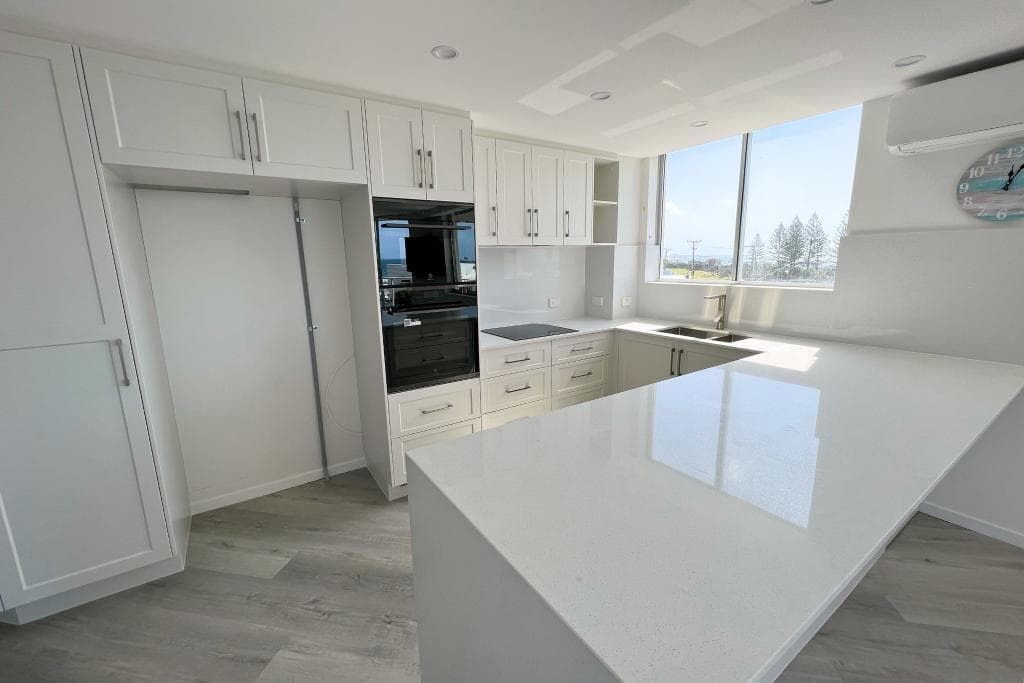 A Kitchen with White Cabinets, White Counter Tops, and A Large Island — Nyblad Construction in Caloundra West, QLD