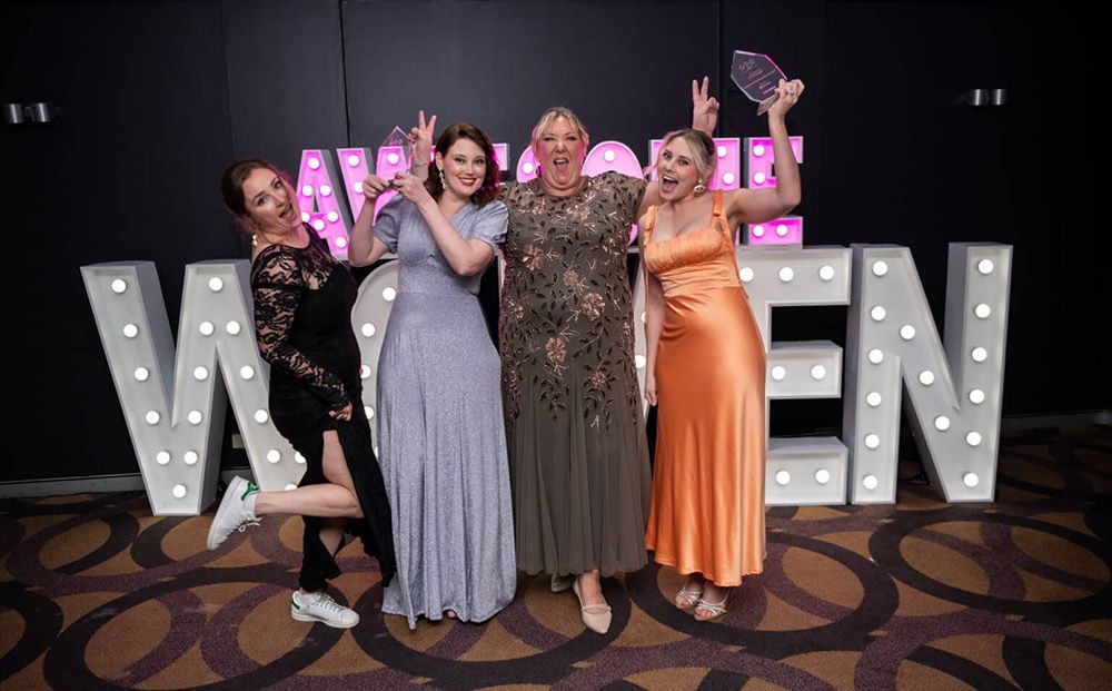 A Group Of Women Are Posing For A Picture In Front Of Large Letters — Nyblad Construction in Caloundra West, QLD