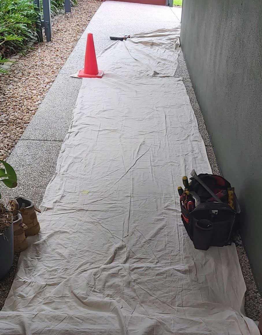 A White Tarp Is Covering A Sidewalk Next To A Red Cone And A Tool Bag — Nyblad Construction in Caloundra West, QLD