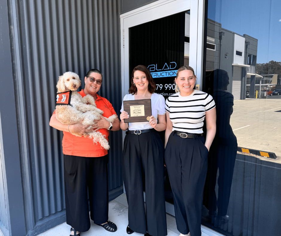 Three Women and a Dog Are Standing in Front of a Building — Nyblad Construction in Caloundra West, QLD