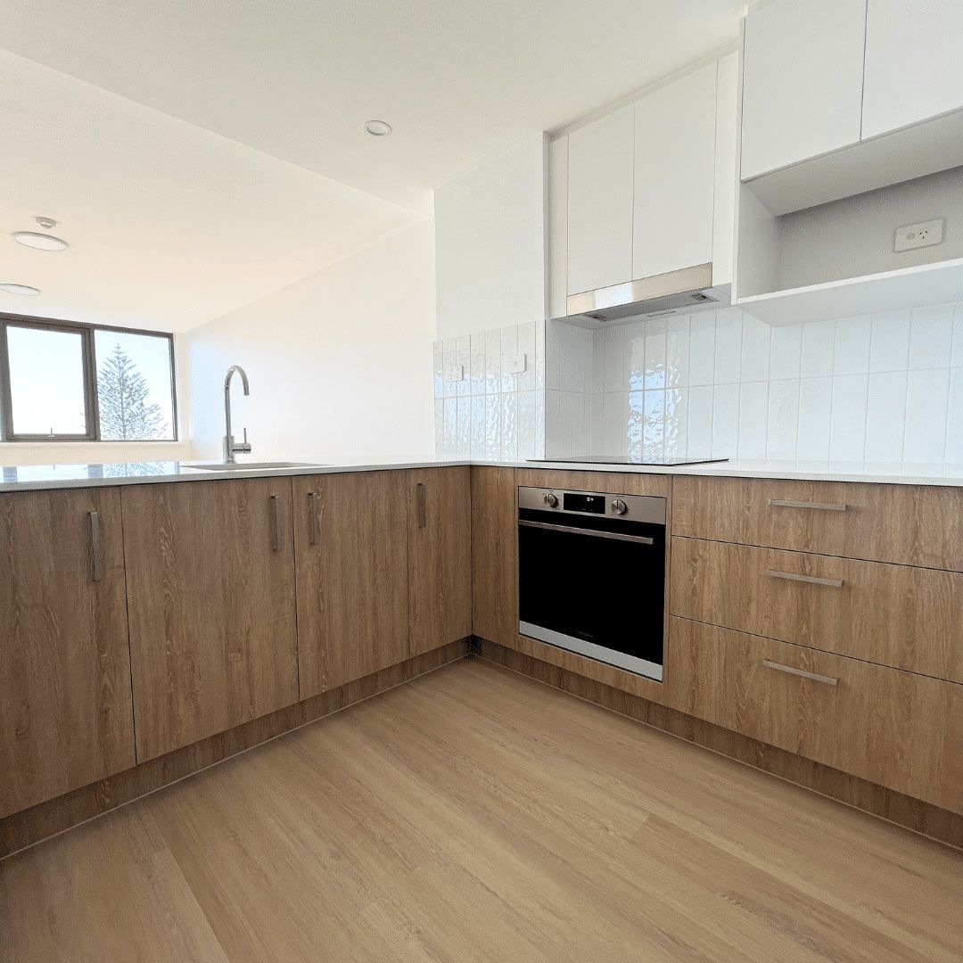 A Kitchen With Wooden Cabinets And Stove Appliances — Nyblad Construction in Caloundra West, QLD